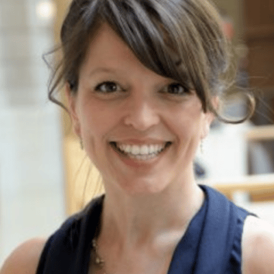 Christine Stephenson smiles for her bio photo. In this photo, she has brown hair and is wearing navy blue.