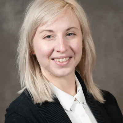 Amanda DeWitt smiles as she wears a white button up and a black blazer. She has light blond hair.