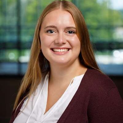 Abby Rudd smiles for her bio picture. She has long, light brown hair and wears a white blouse and black blazer.