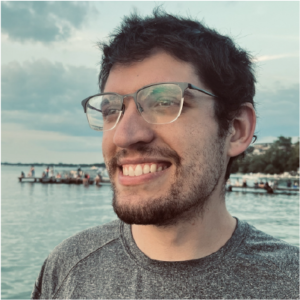 Headshot of man wearing glasses standing by the lakeshore